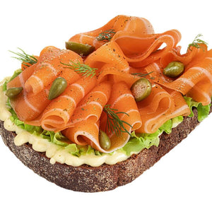 Open-faced plant-based smoked salmon sandwich with lettuce, capers, dill, and creamy spread on rye bread