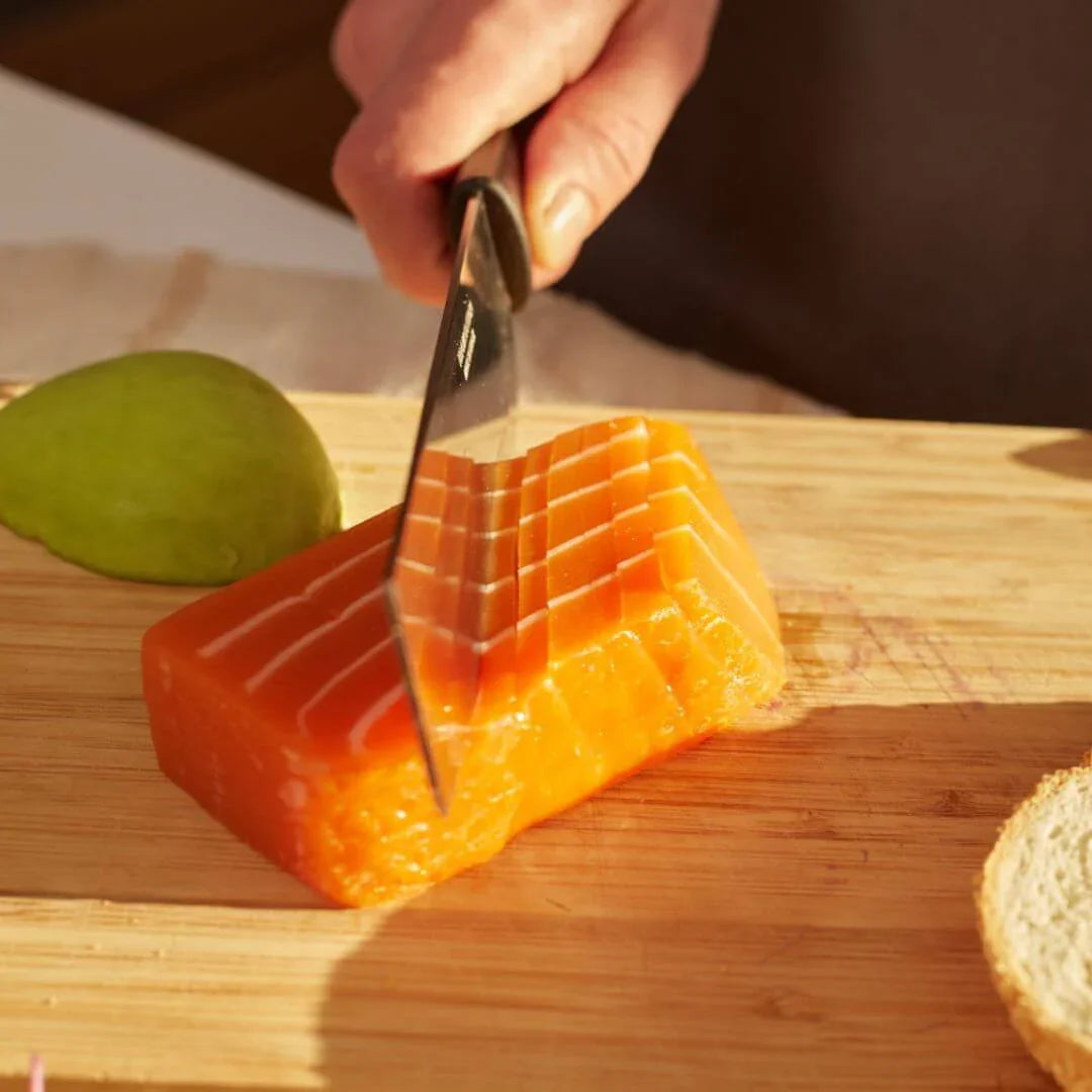 Hand slicing plant-based salmon sashimi block on wooden board, vegan seafood by WELAZA UAE
